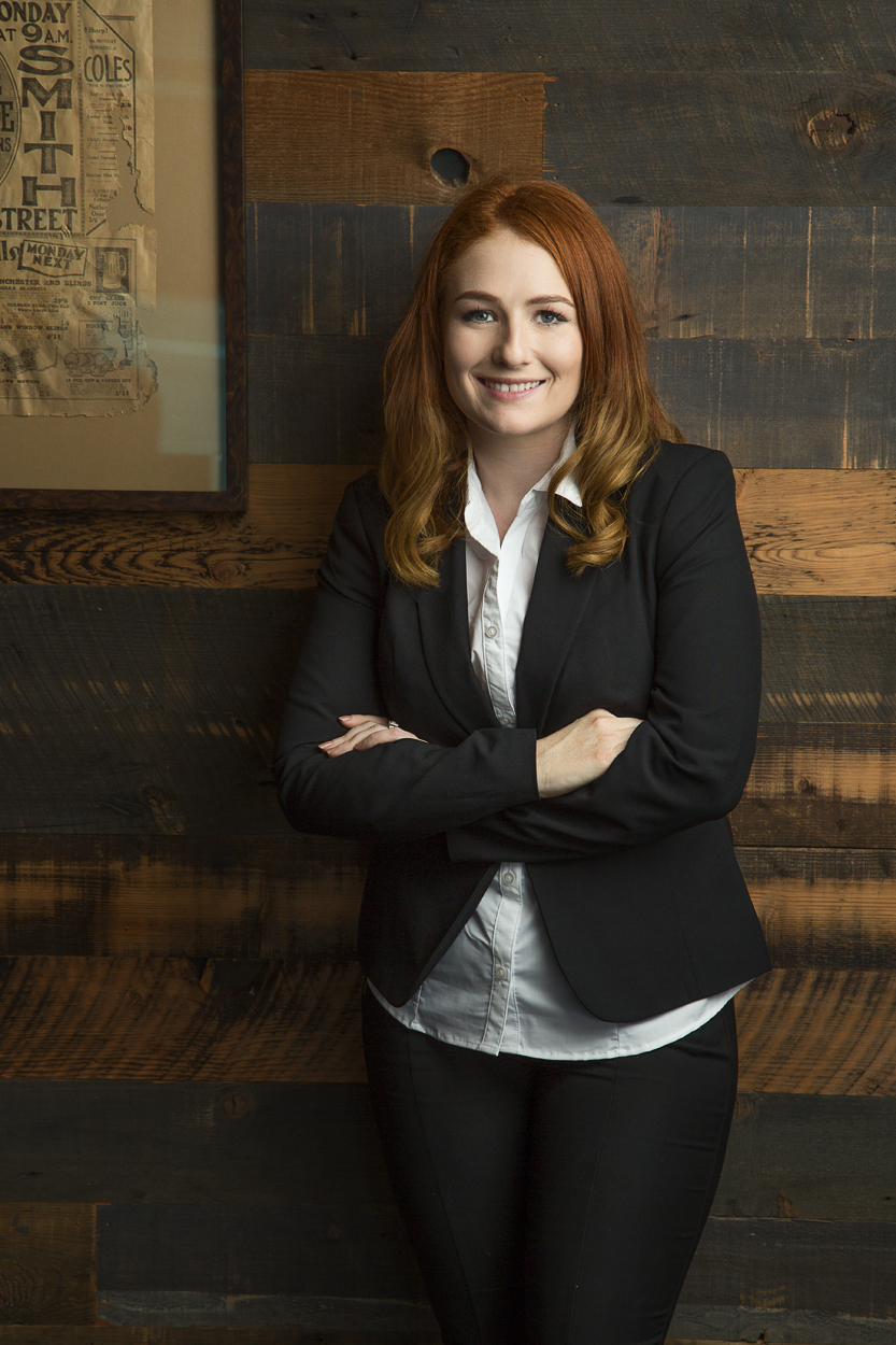 Portrait of a business woman with crossed arms leaning against timber wall