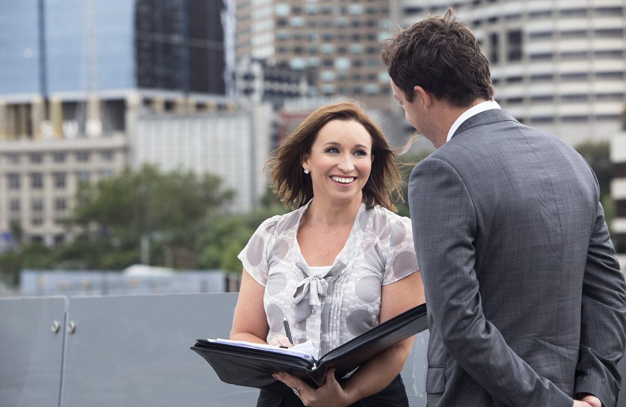 Business woman talking to client in front of city backdrop