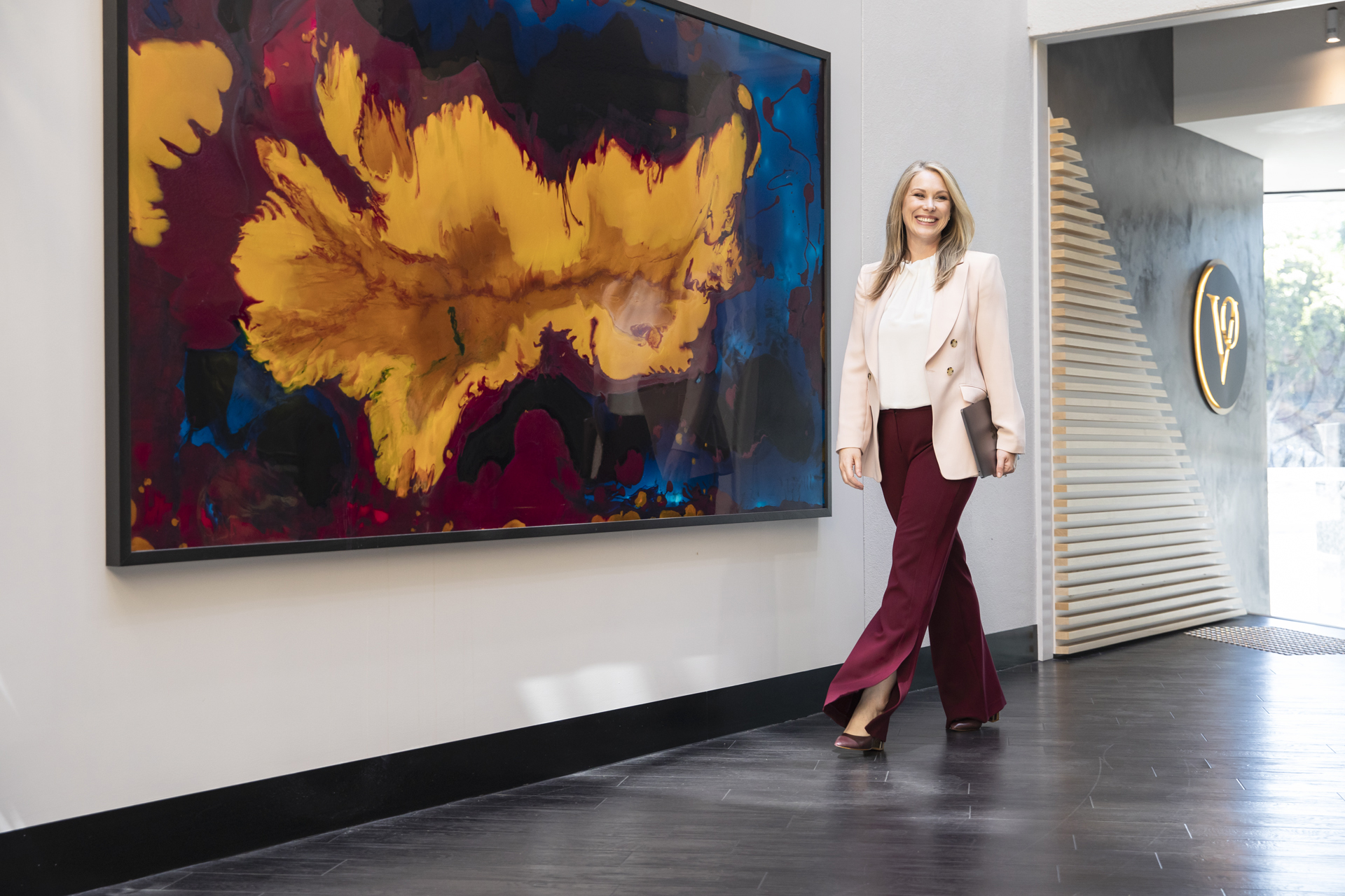 Business woman carrying laptop and walking past artwork