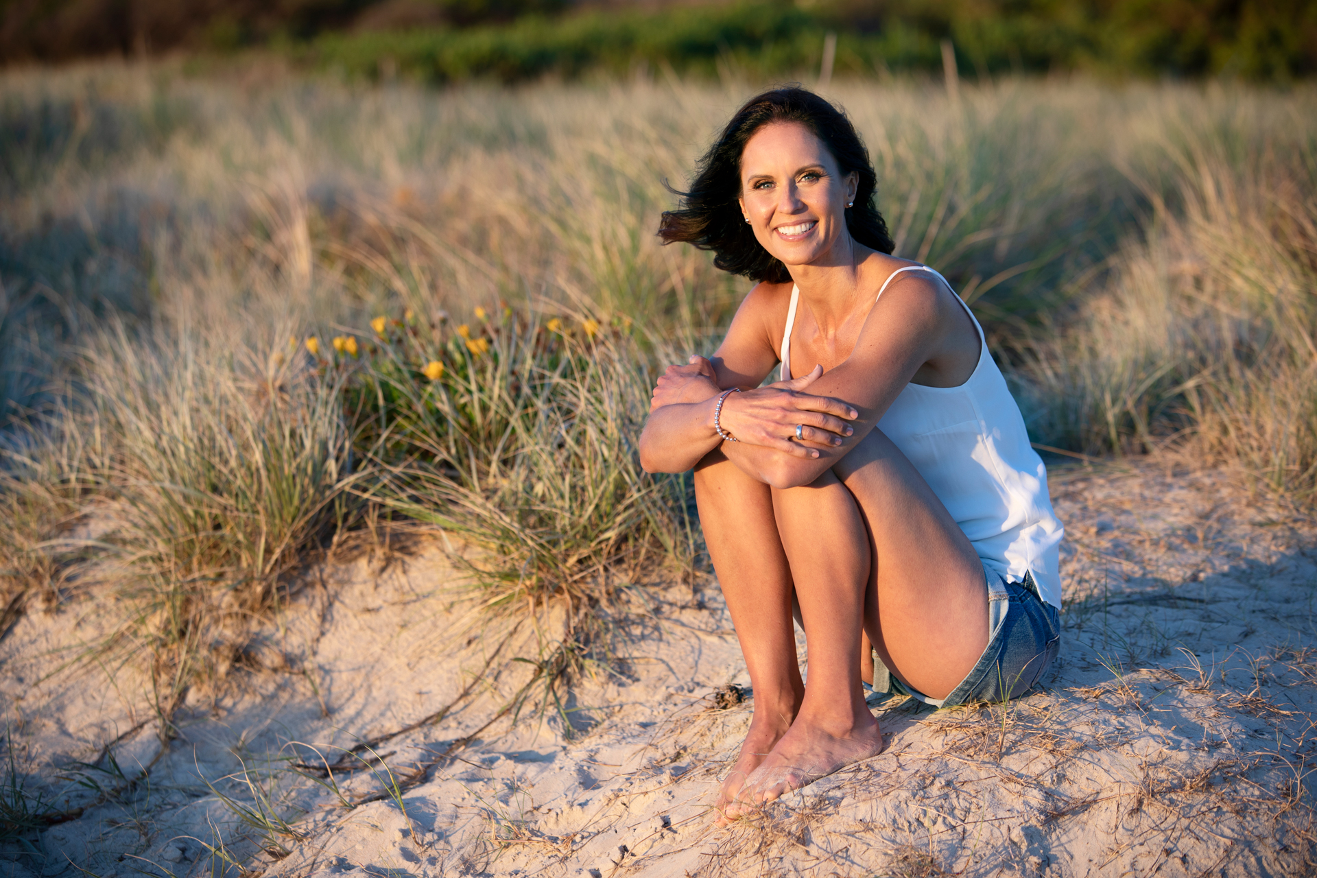 Lady sitting in long grass at the beach