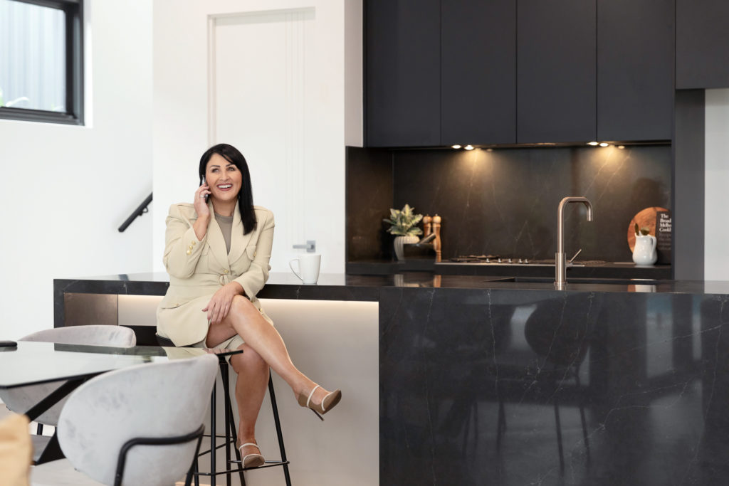 Business woman sitting at kitchen bench talking on her mobile