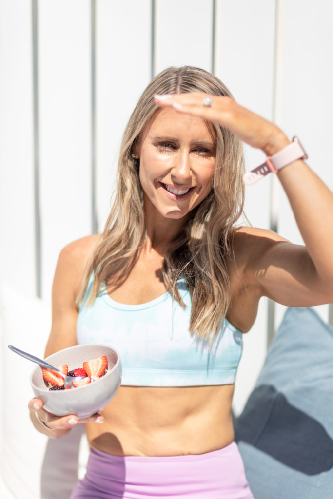 female fitness professional holding a bowl of cereal with berries