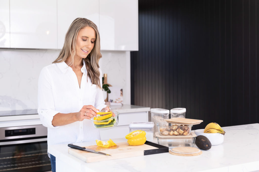 Female Nutritionist at the kitchen bench preparing and storing meals