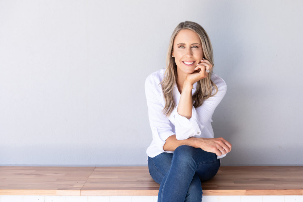 Female business owner sitting on a bench against a light grey wall