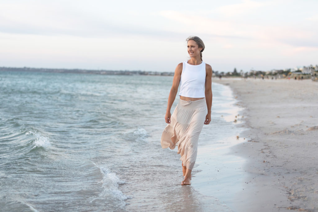 Female business owner walking along the beach at dusk