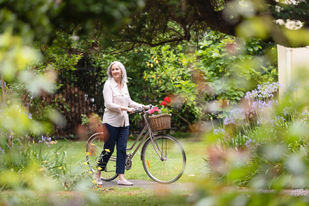 Lady walking her bicycle through a garden