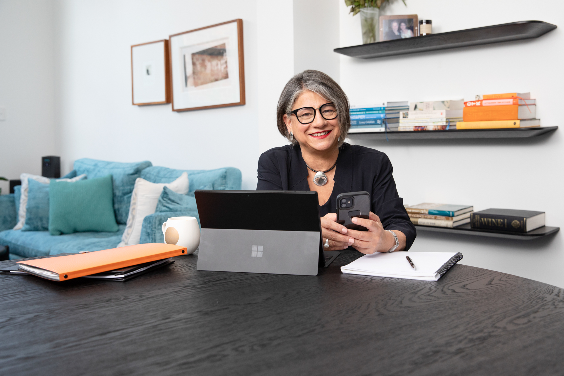Business woman sitting at table with laptop and holding her mobile phoone