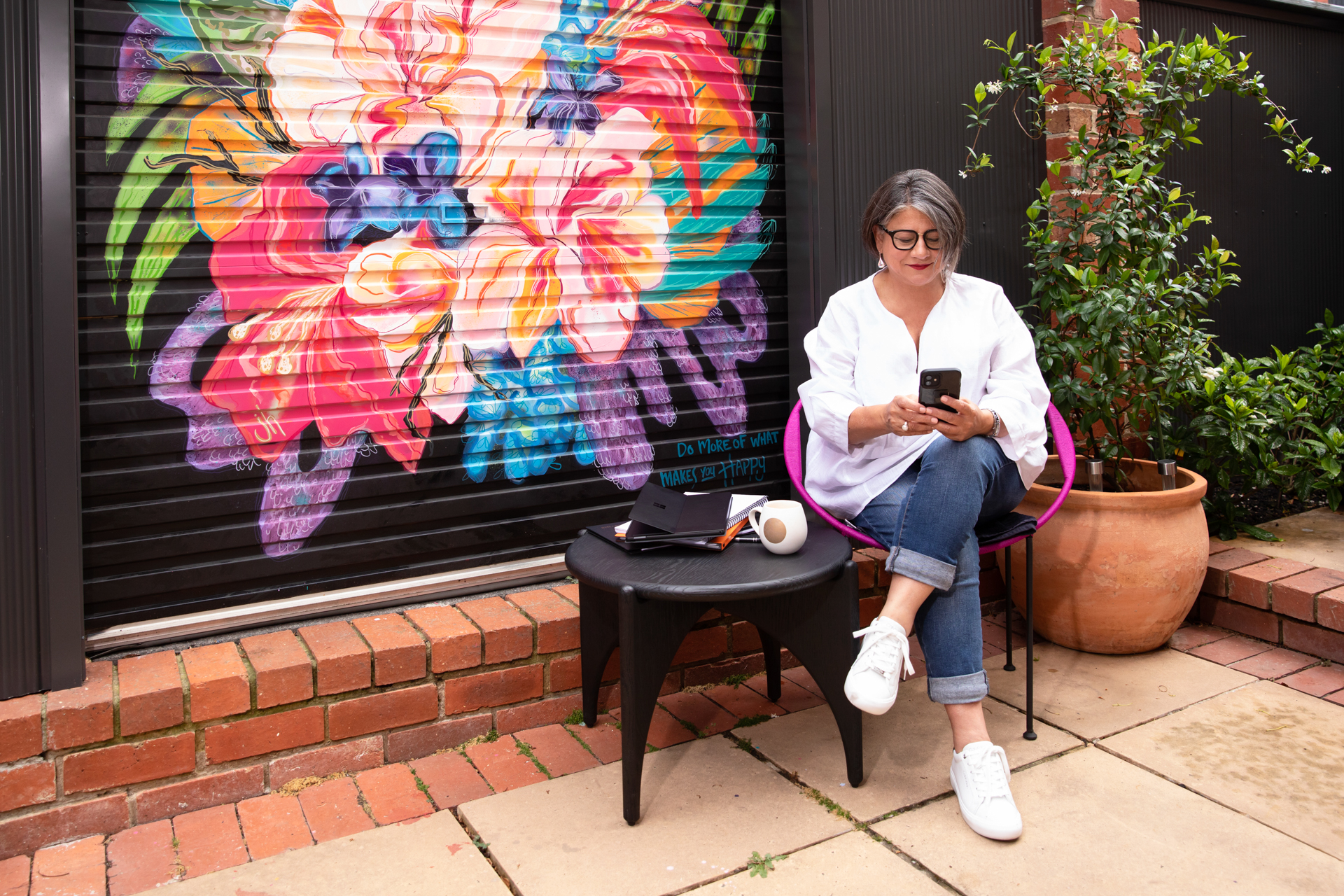 Business woman sitting in her court yard with phone