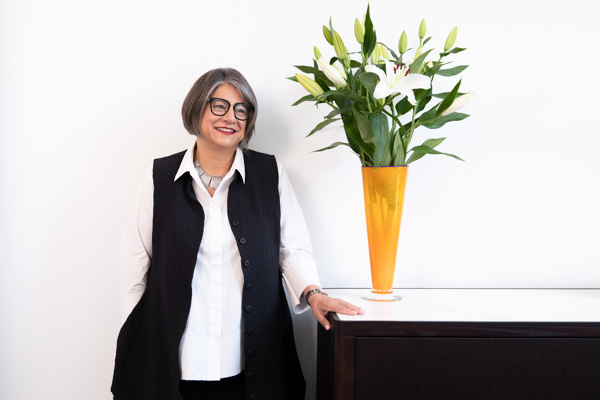 Portrait of a female business owner standing next to a vase of lillies