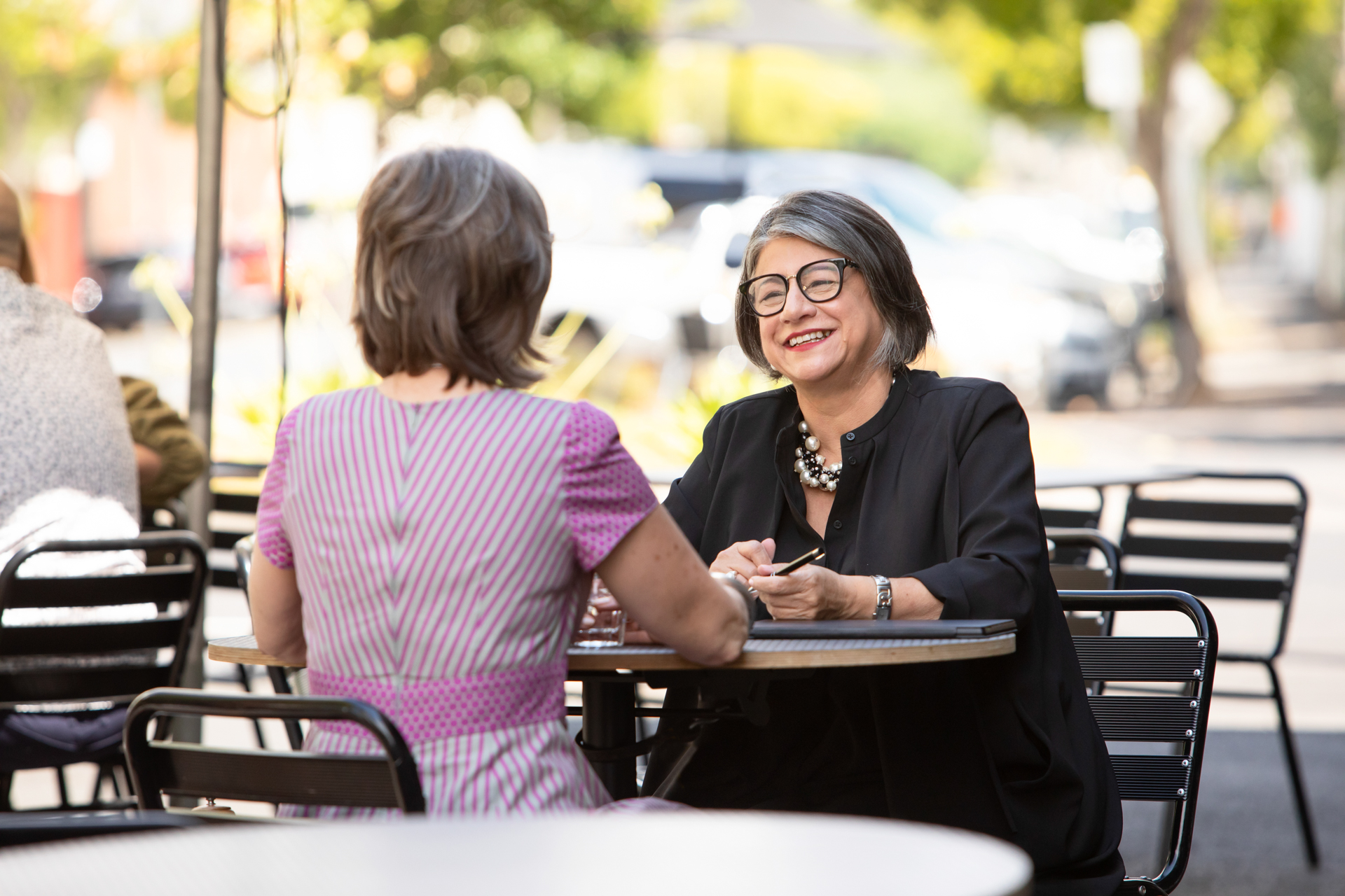 Female business owner chatting with a client at an outdoor cafe table