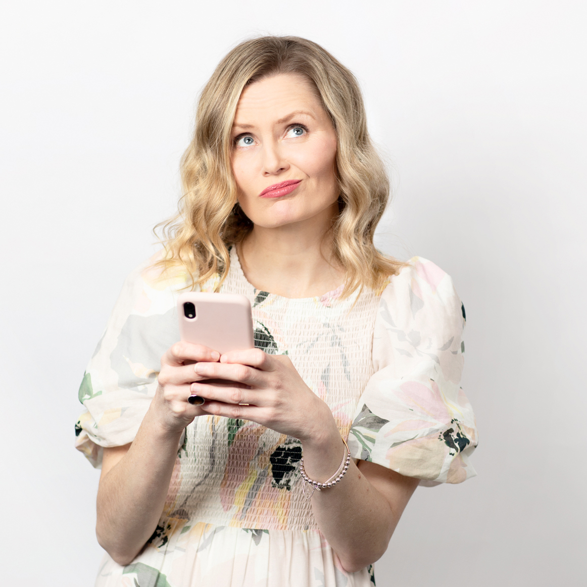 Woman holding mobile phone with quizzical look on face