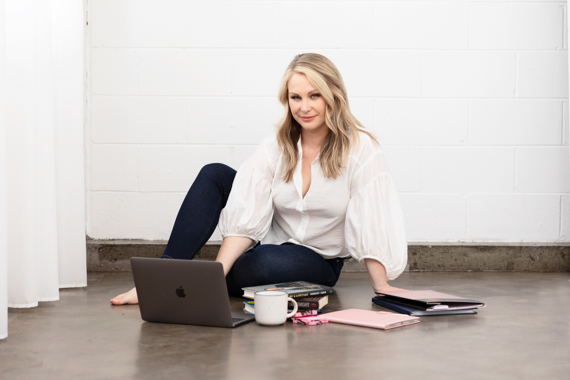 personal branding photo of a presentation coach sitting on the floor while working on a laptop