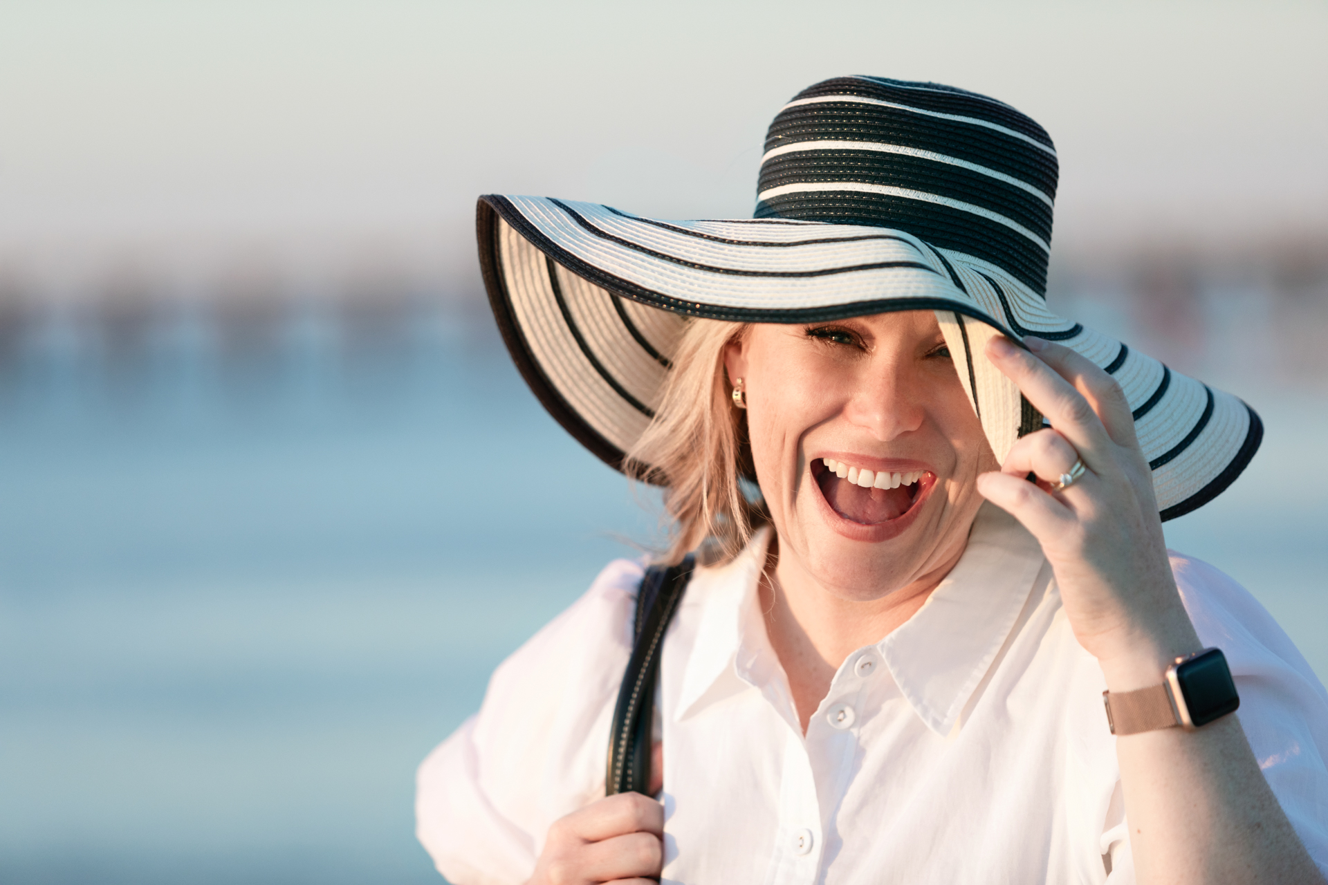 personal branding photo of a female business owner at the beach wearing a sunhat