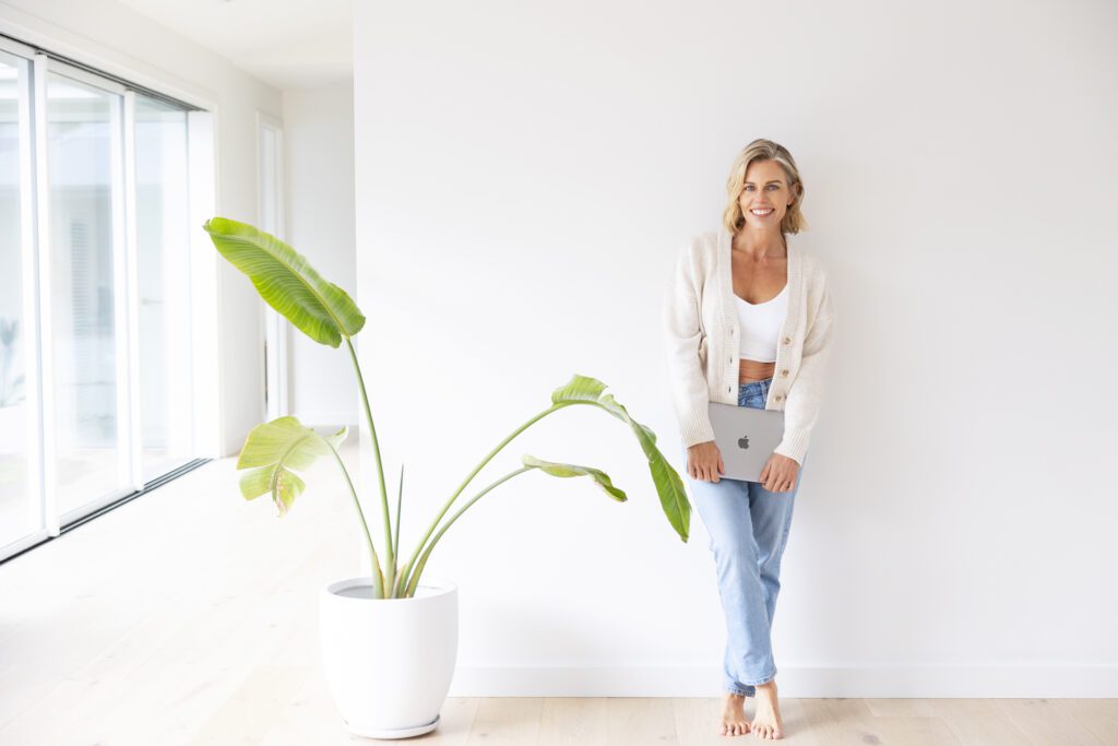 Lady leaning against a wall holding her laptop