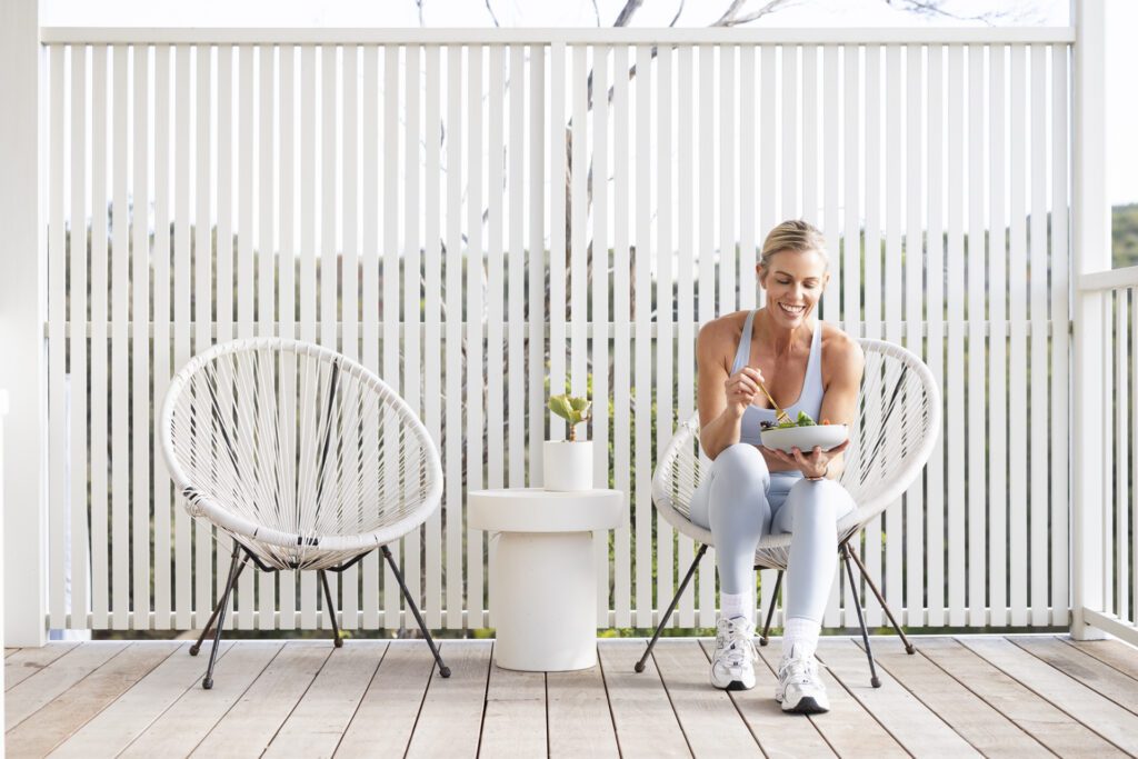 Lady sitting on a deck chair eating a salad