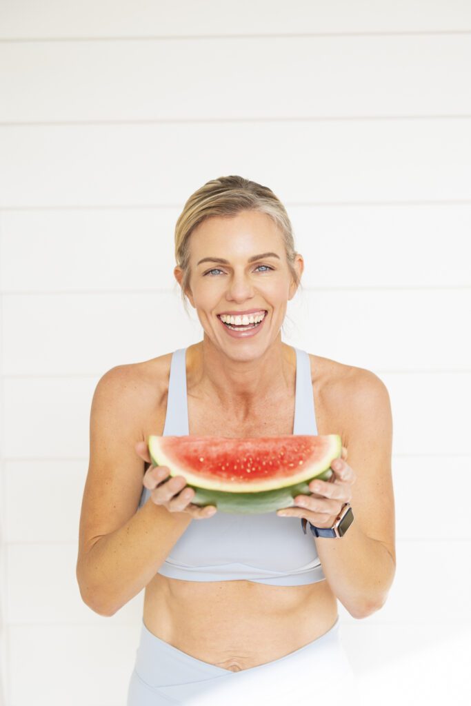 Lady holding a watermelon slice and laughing at the camera