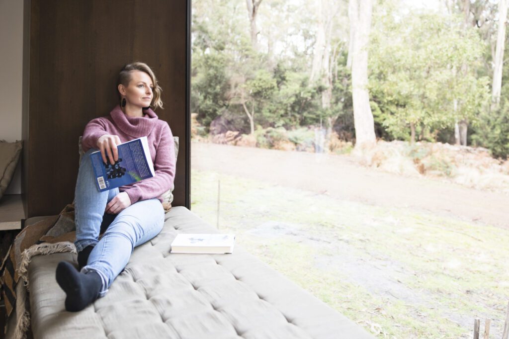 Picture of a lady sitting in a window seat holding a book