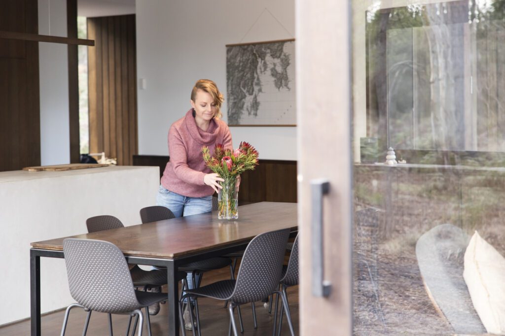 Image of a lady putting a vase of flowers on a table