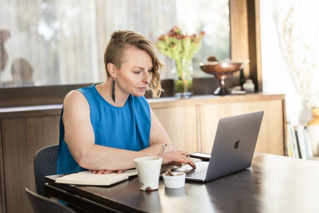 Lady sitting at a dining table working on her laptop