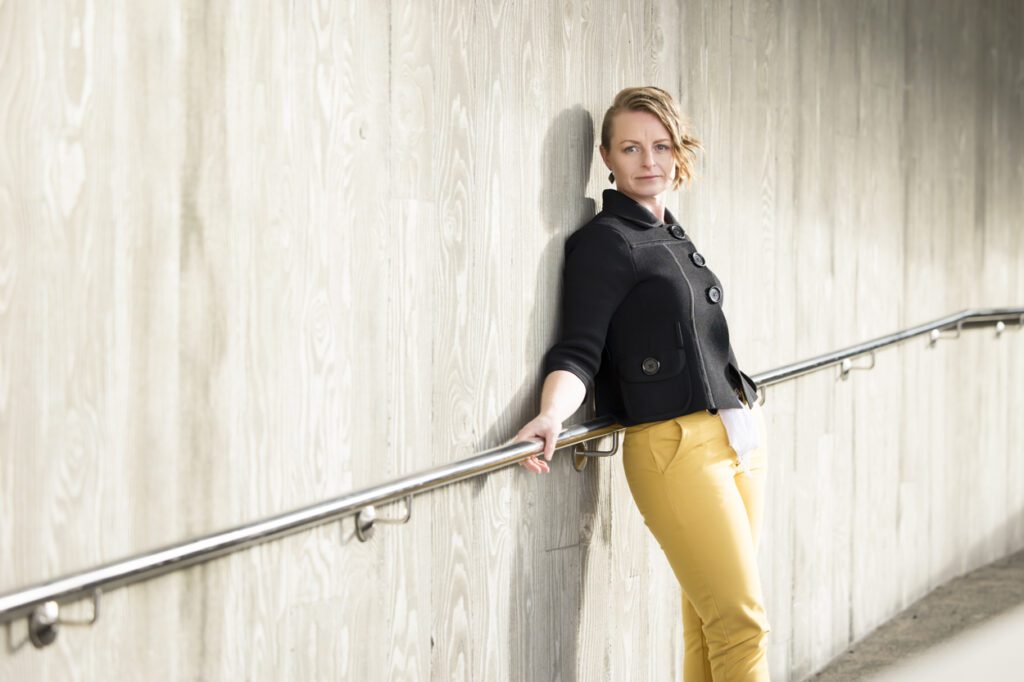 Lady leaning against a concrete wall