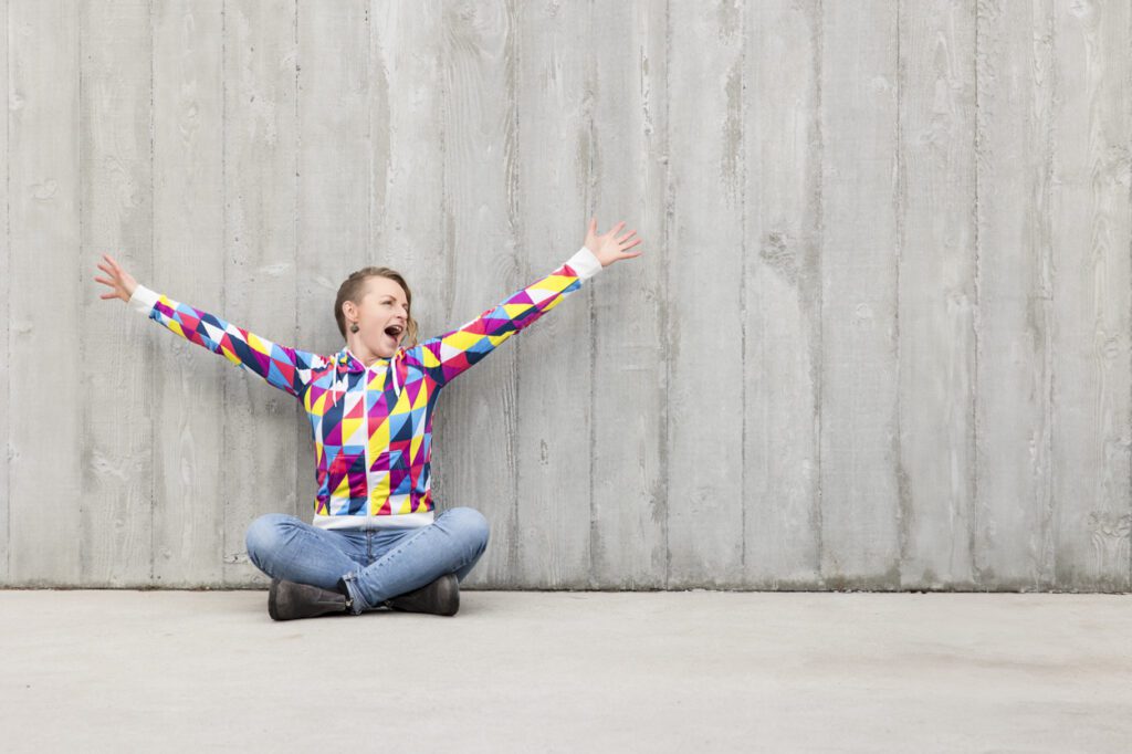 Lady sitting on the ground with her hand in the air feeling joy.