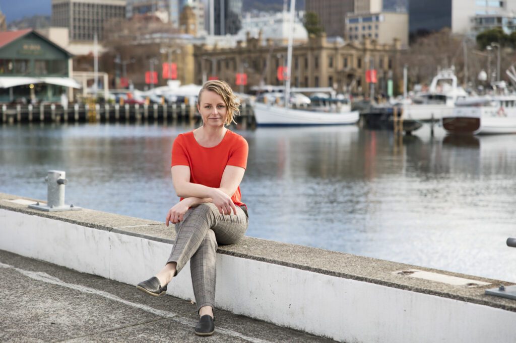 Lady sitting on the dock with with boats and city in the background