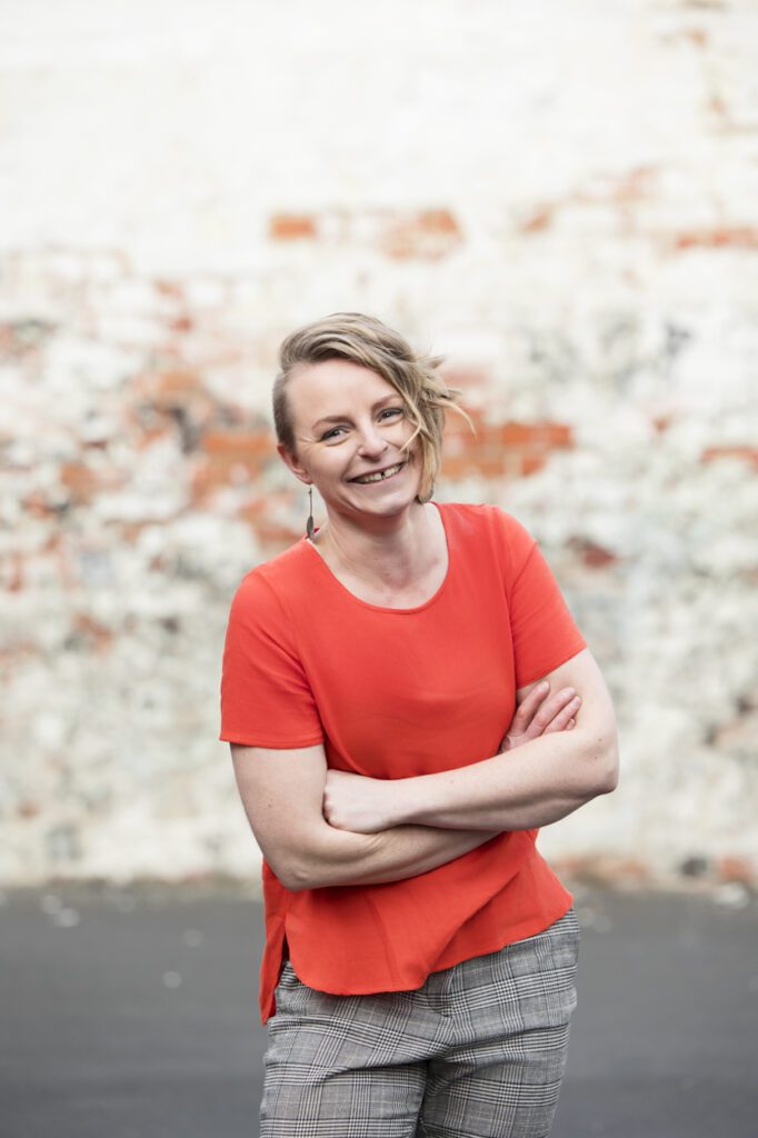 Portrait of a lady with her arms crossed laughing at the camera