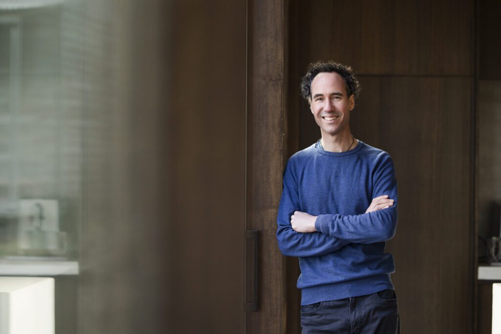 Portrait of a man leaning against a wooden pole