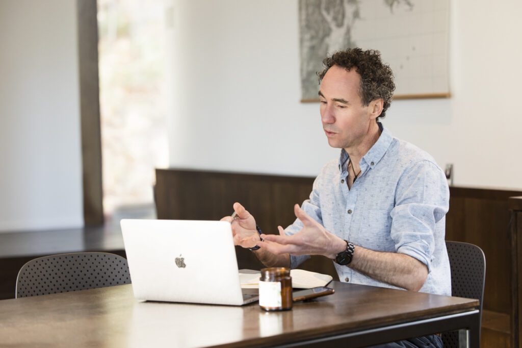 A man in an online meeting talking to his laptop