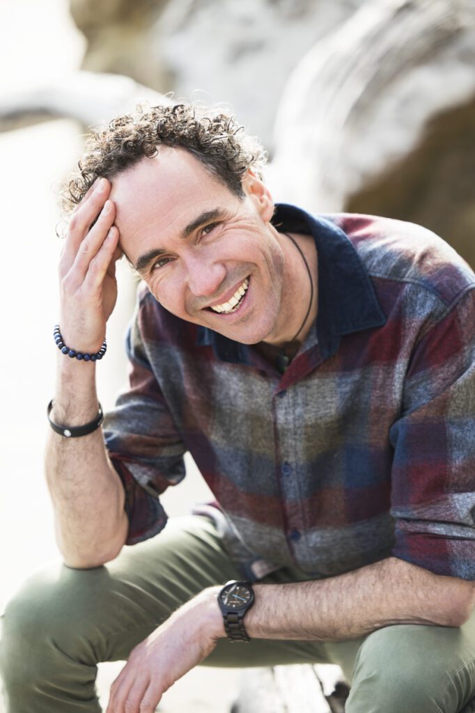 Portrait of a man sitting down and running his hand through his hair