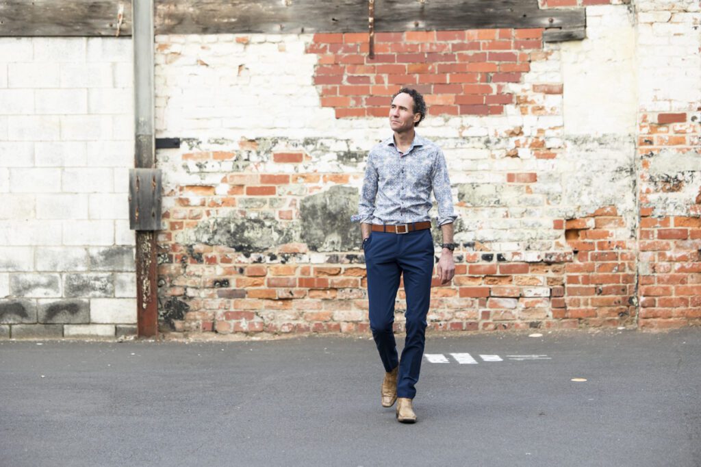 A man walking with a weathered brick wall in the background