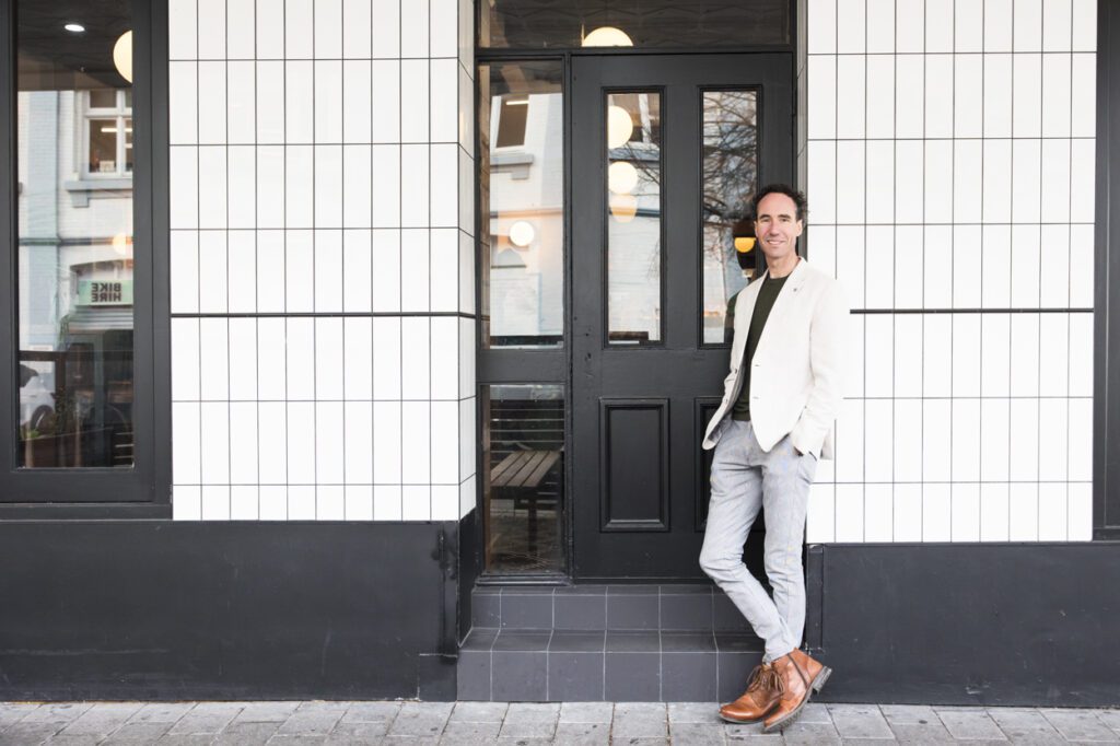 A man in the doorway of a hotel leaning against the wall