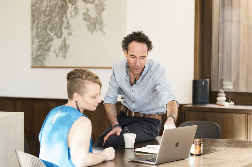 A man and a lady talking and looking at the screen of a laptop