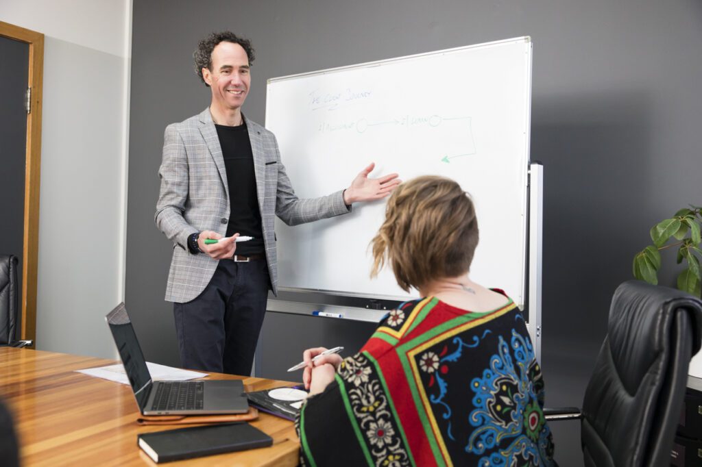 A man explaining a concept that's on a white board