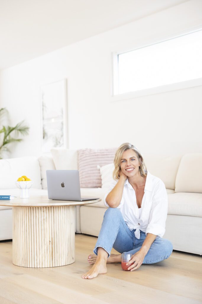 Lady sitting on the floor next to a coffee table where she has her laptop