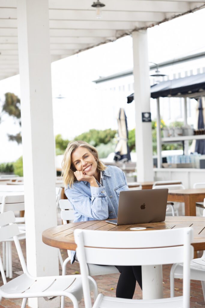 Lady sitting at a cafe table doing work on her laptop