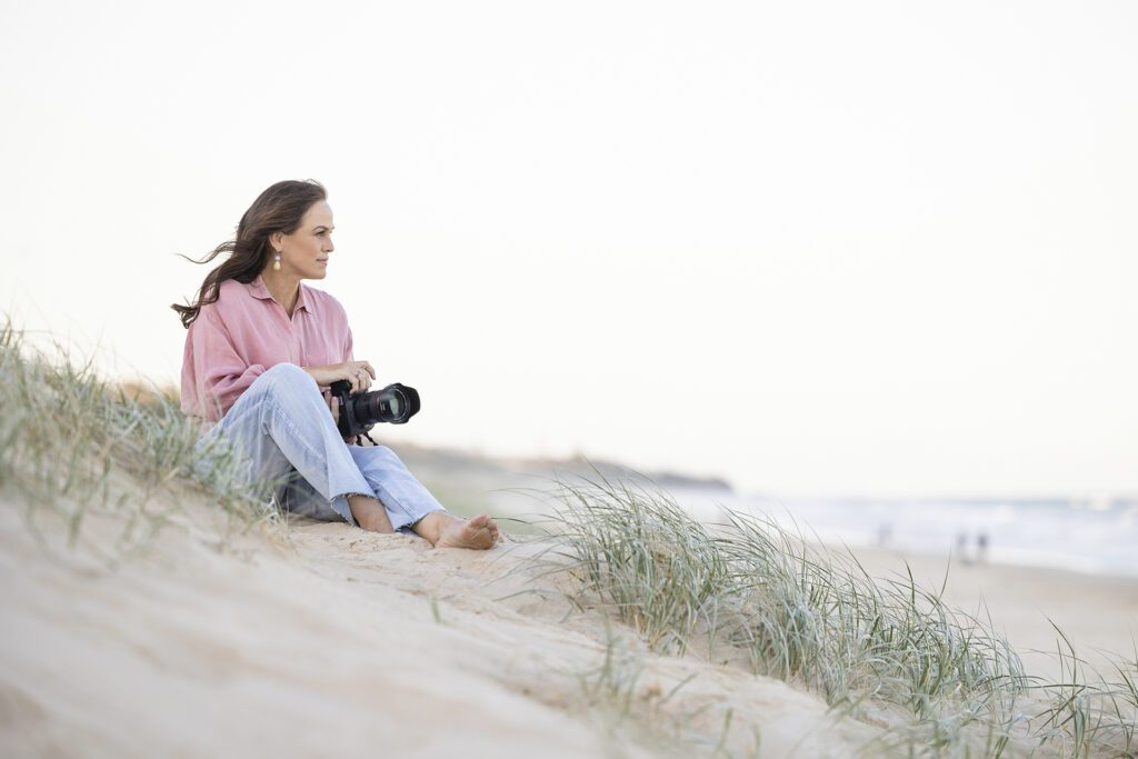 Photographer sitting on a beach looking out to the water