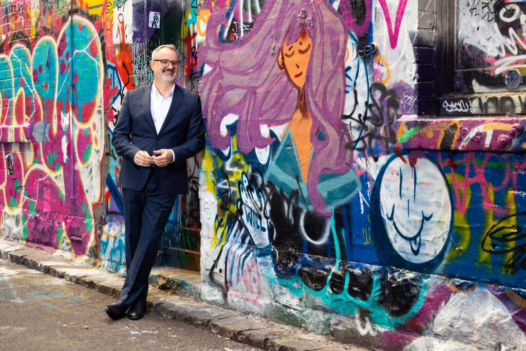 Man leaning againts a graffiti wall