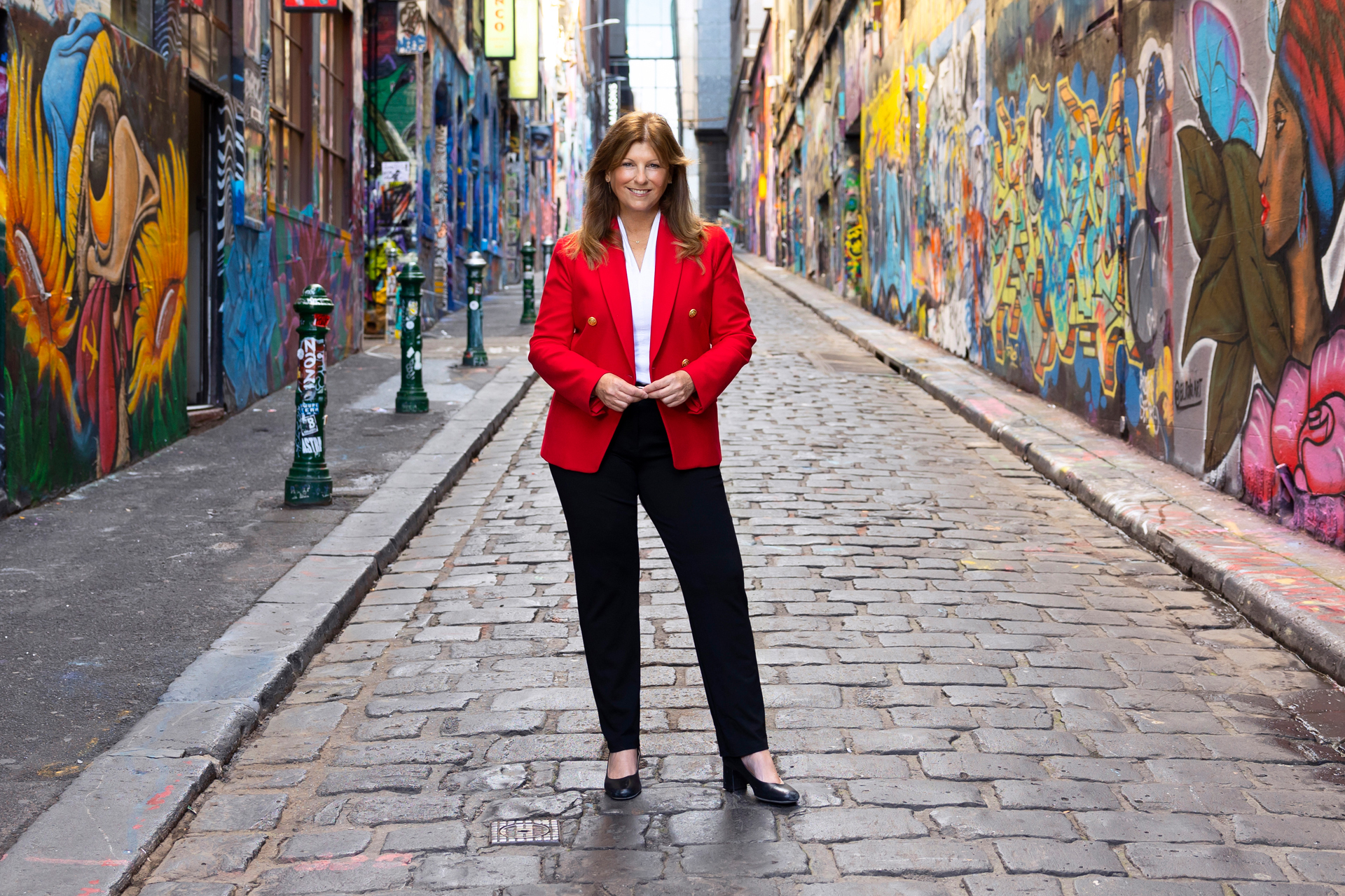 Lady standing in the middle of a lane way with graffiti on the walls