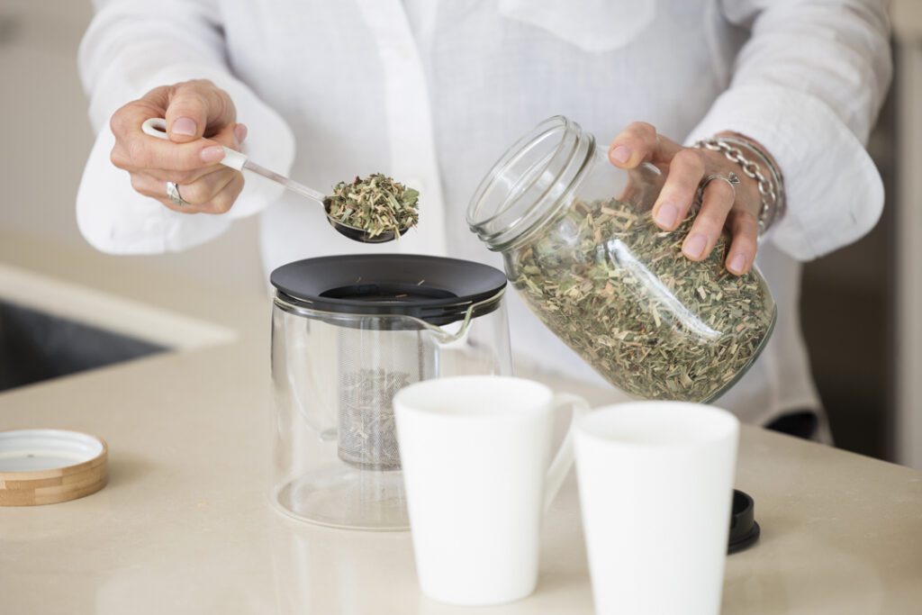 A person putting a spoonful of tea leaves into a teapot - personal brand photoshoot