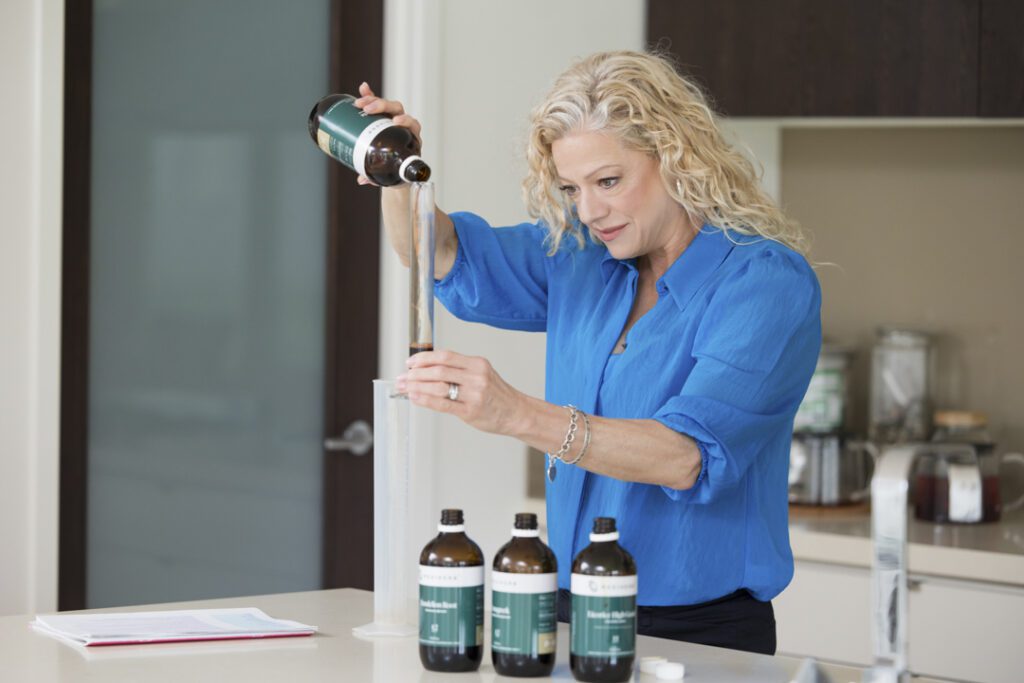 A lady wearing a blue shirt measuring out oils for a tincture - captured on a personal brand photoshoot