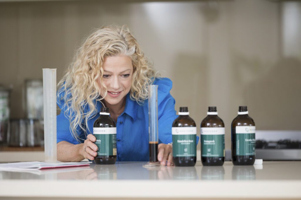 A lady wearing a blue shirt measuring out oils for a tincture - captured on a personal brand photoshoot