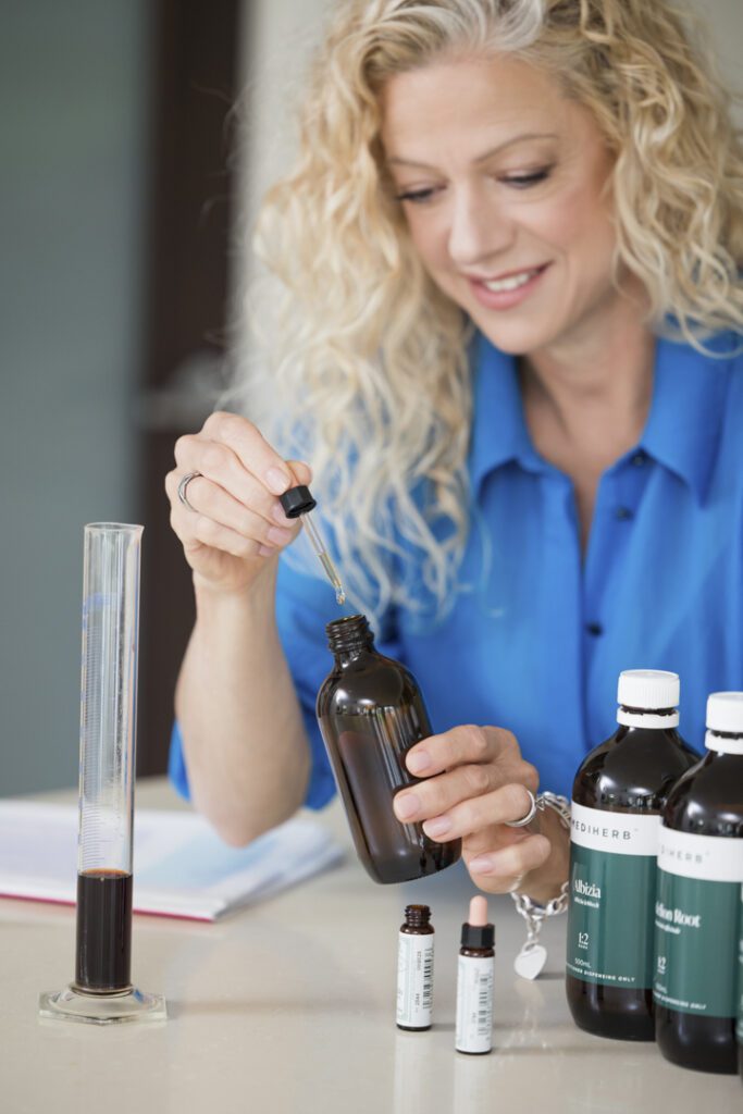 A lady wearing a blue shirt measuring out oils for a tincture - captured on a personal brand photoshoot