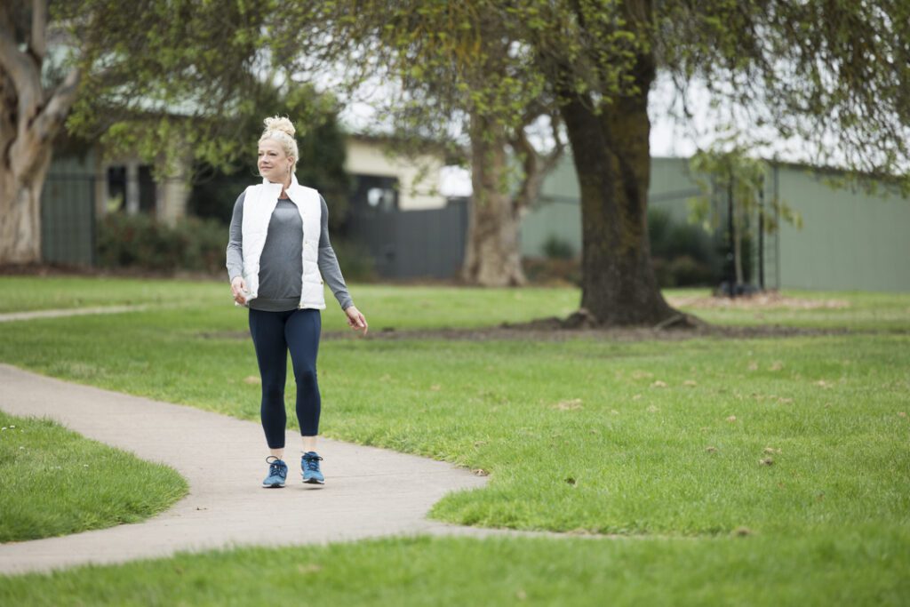 A lady wearing fitness attire walking along a path in a park - captured on a personal brand photoshoot