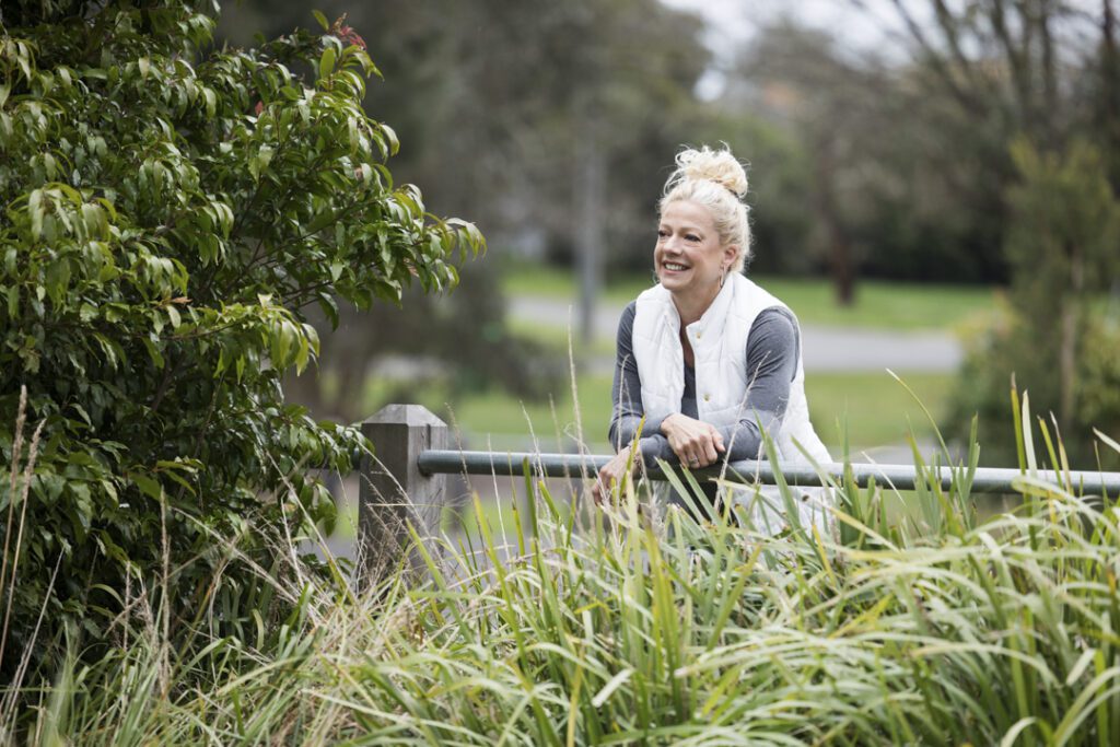 A lady wearing fitness attire leaning over a fence railing in a garden - personal brand photoshoot