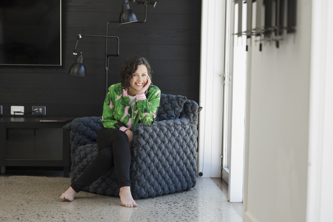 Lady sitting in comfy chair cradling her chin in her hand