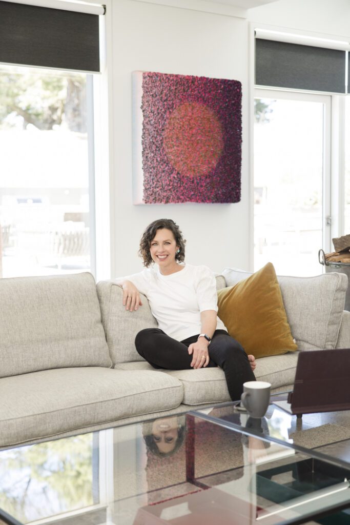 A lady wearing a white top and black jeans sitting on a couch