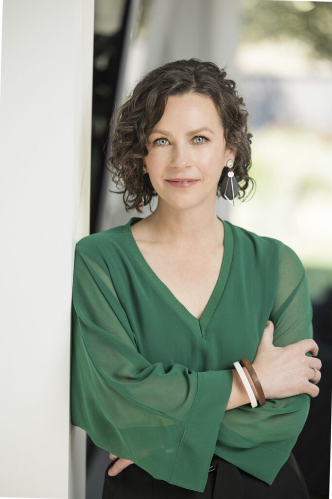 A lady wearing a green top who leaning against a wall