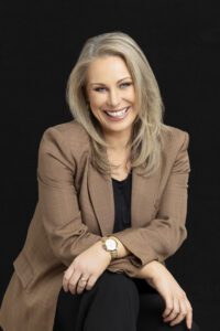 A personal brand photoshoot that captures a portrait of a lady in a brown jacket with a black background