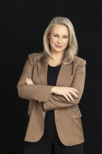 A personal brand photoshoot that captures a portrait of a lady in a brown jacket with a black background